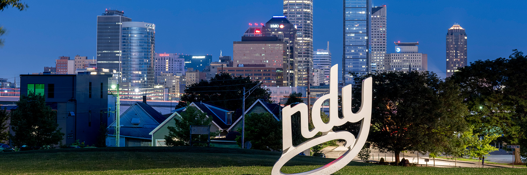 Photo at night of the Indianapolis skyline with the Indy sign in the foreground.