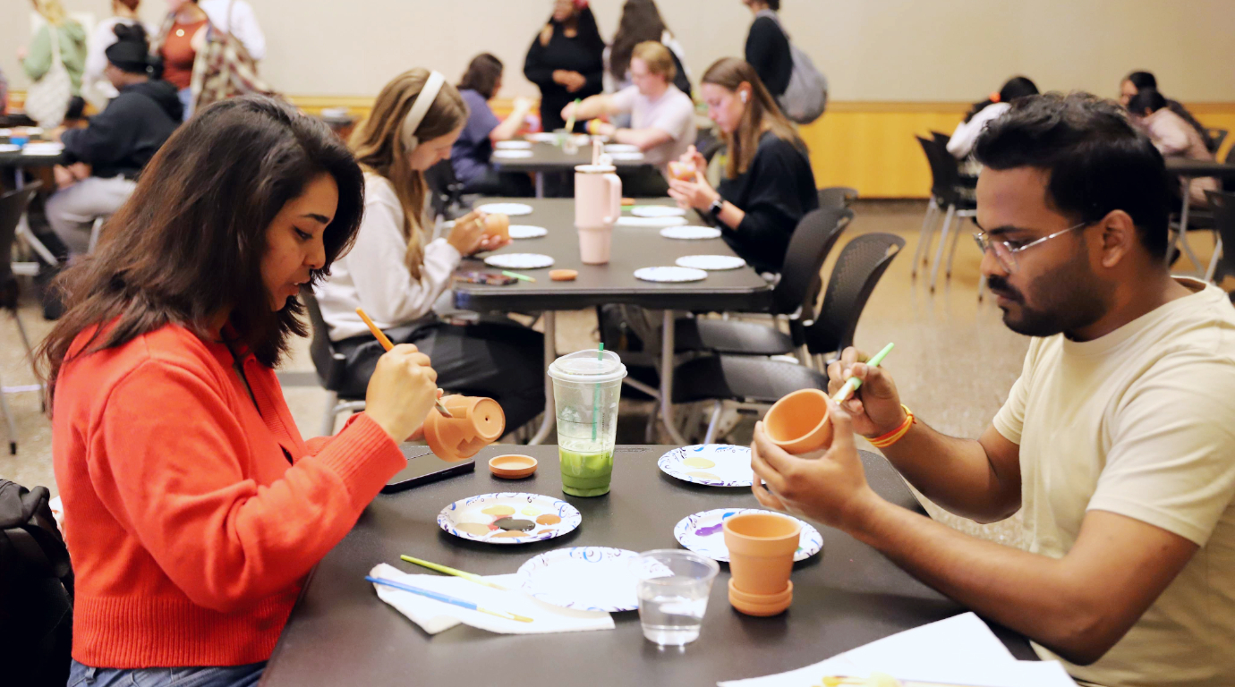 Two students painting pots at a Stress Busters Week event