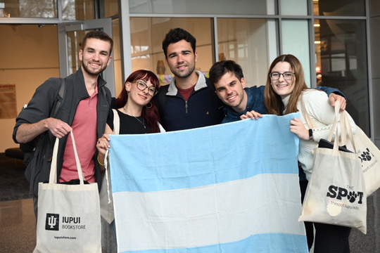 A group of people holding an Argentinian flag.
